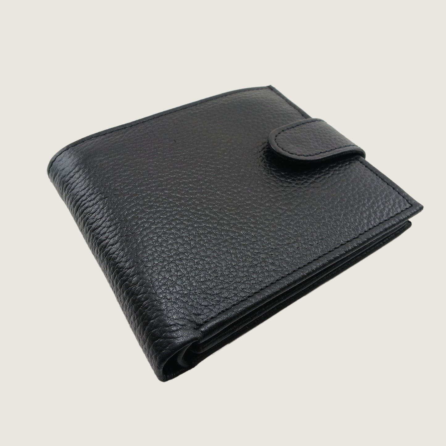 A black textured leather bifold wallet with a snap-button tab closure, shown on a light beige background.