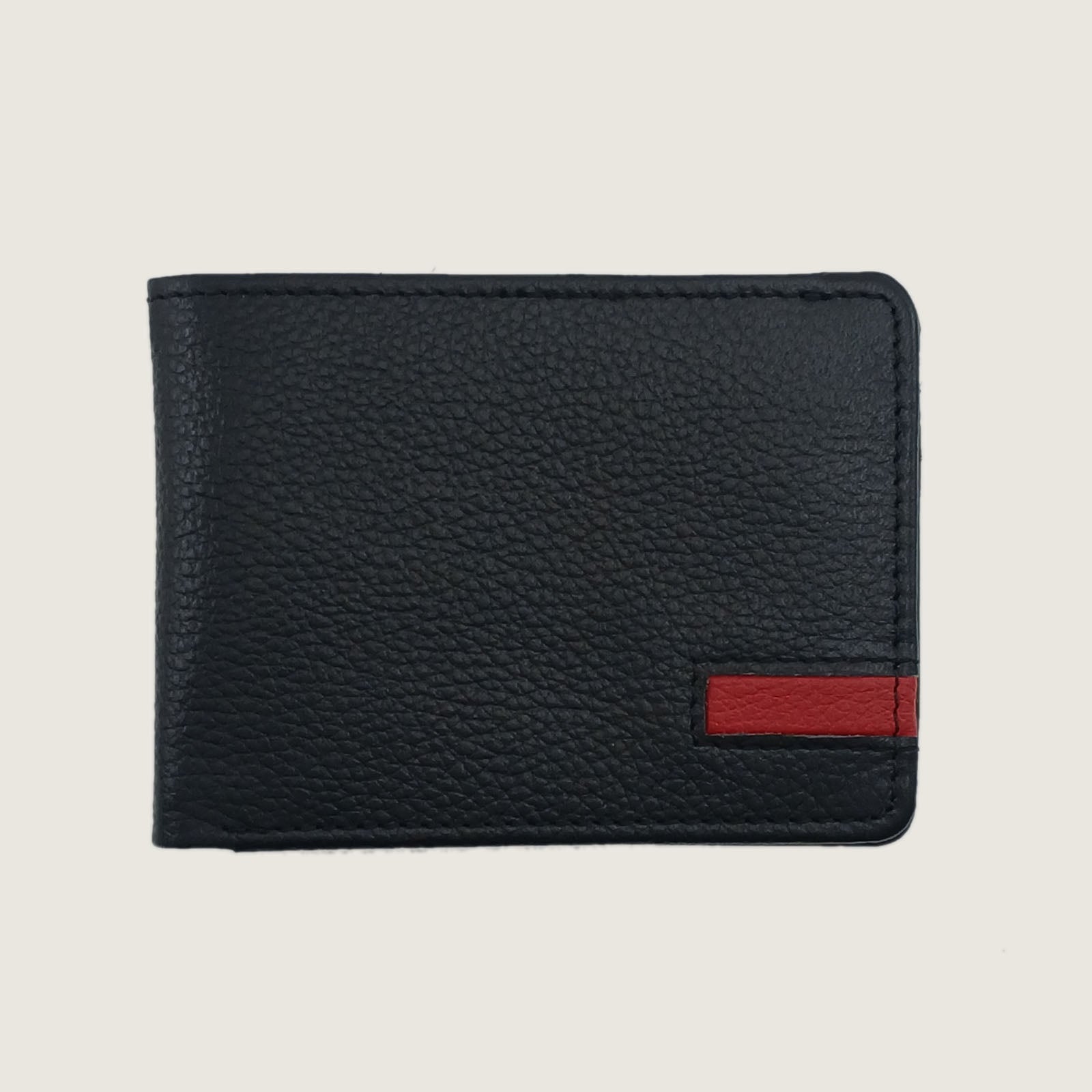 A black pebbled leather bifold wallet with a small red accent tab on the lower right, shown against a light beige background.